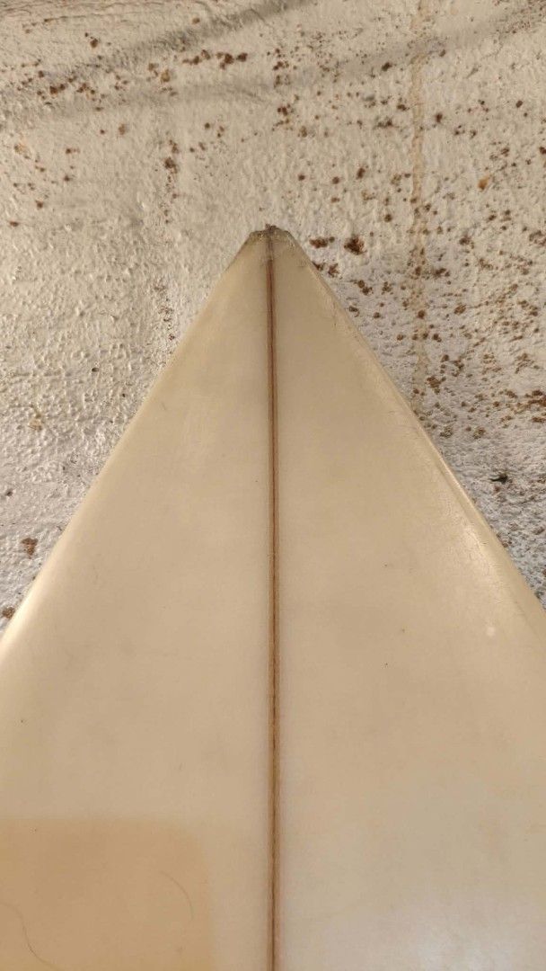 Brothers Neilsen Surf Surfboard (Category: Swim Trunks & Board Shorts) located in Manila. Submitted by glydelmalu86312 (Listing ID 1465320330, Image 3). Description: - Brand/Model: Brothers Neilsen surf board with Benson traction pad - Design: Classic white finish with central wooden stringer from nose to tail - Setup: Tri-fin configuration - Condition: Well-loved with wax residue, minor dings near the nose, a repaired patch near the logo, and a 