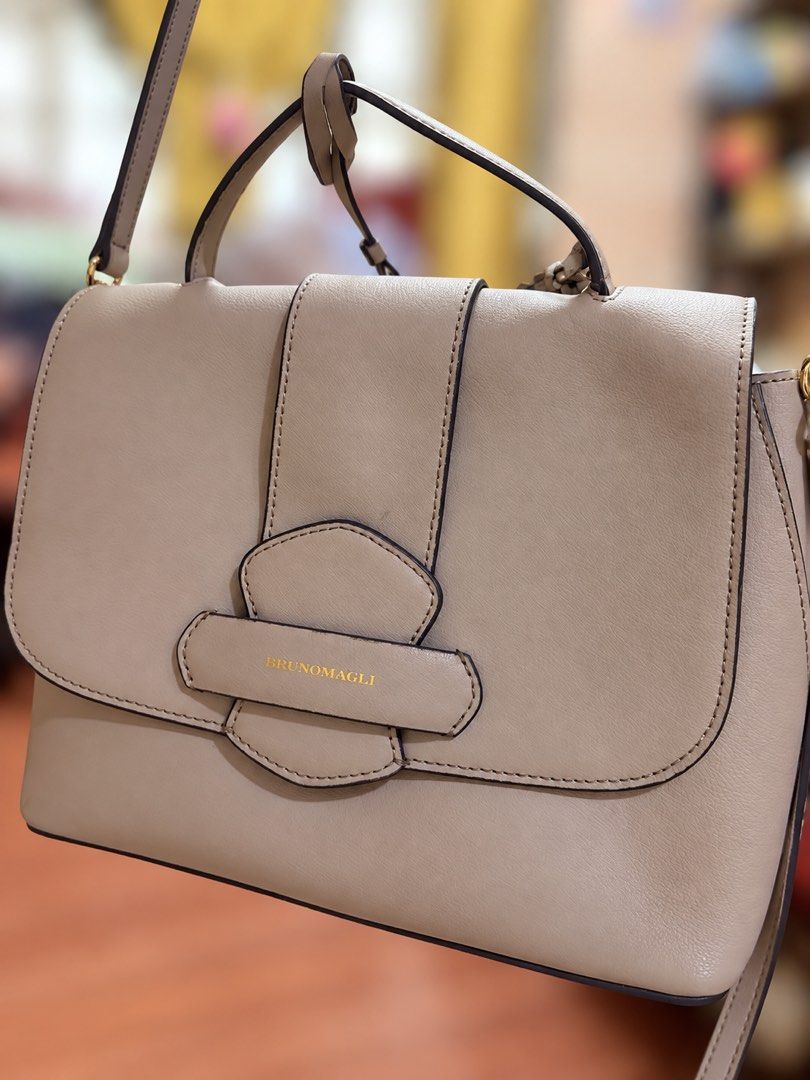 BRUNOMAGLI Beige Leather Shoulder Bag (Category: Shoulder Bags) located in Manila. Submitted by lynnalec25 (Listing ID 1465362662, Image 1). Description: - Brand: Bruno Magli - Color: Neutral beige - Material: Premium leather with clean contrast edge glazing - Design: Structured flap with stylish vertical strap accent and gold-tone lettering - Versatility: Includes a sturdy top handle and a detachable shoulder strap with clasp hardware - Conditio