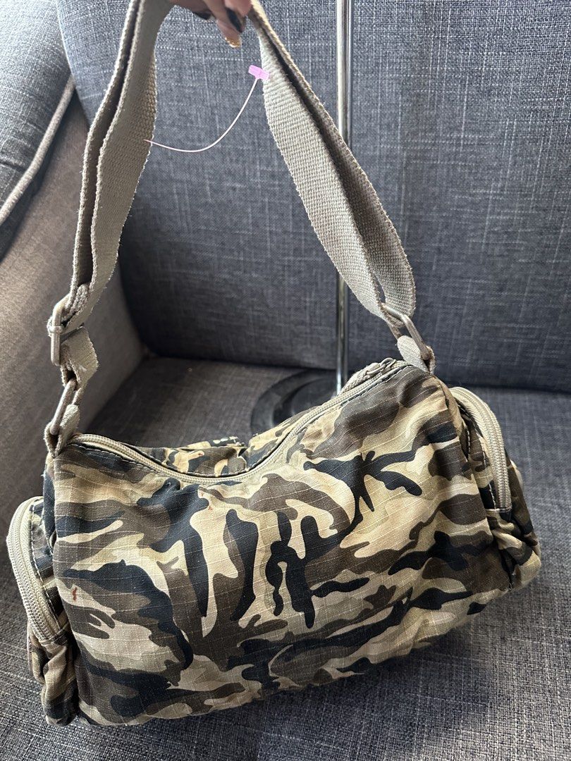 Camo shoulder bag with front pockets and studs (Category: Shoulder Bags) located in Manila. Submitted by goldenhorse-dafc (Listing ID 1465376069, Image 2). Description: Camo print shoulder bag made from canvas material. Thick strap with adjustable metal buckles. Two front pockets with magnetic buckles and silver studs. Zipper closure across the top. Side zipper pockets for extra storage. Inside lined with fabric, includes a small zippered side po