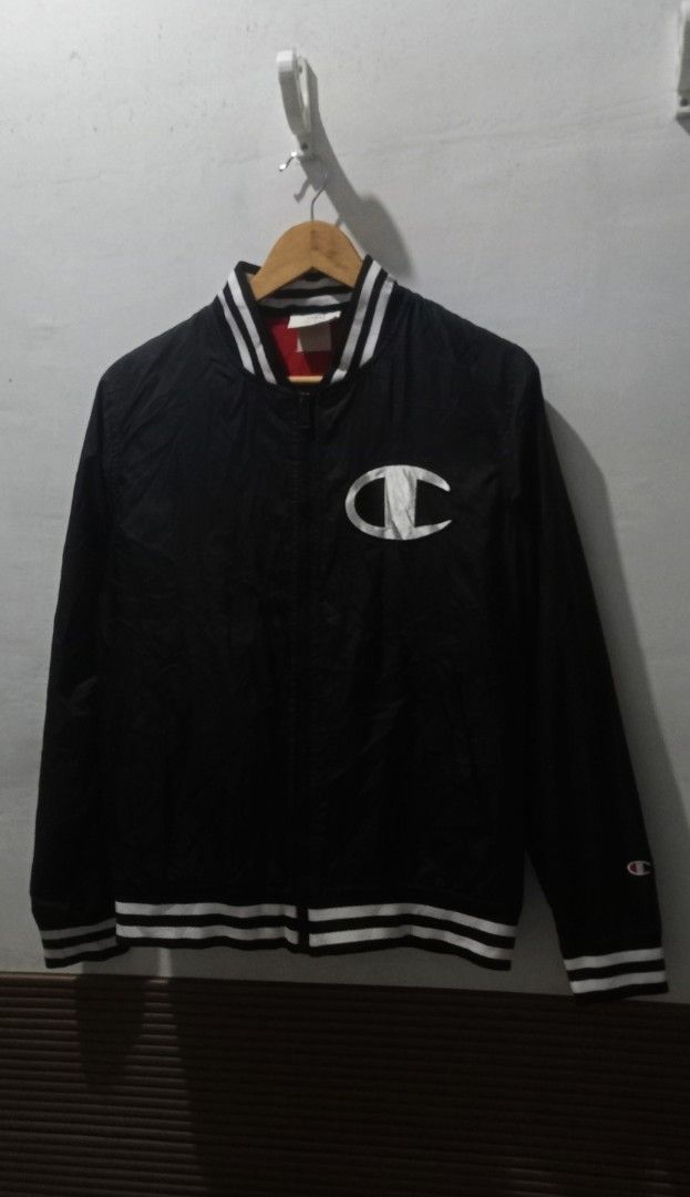 Champion Black Bomber Jacket Size Large (Category: Coats, Jackets and Outerwear) located in Taguig. Submitted by mvdsh0p2022 (Listing ID 1465273895, Image 1). Description: - Brand: Champion - Style: Bomber Jacket - Color: Black with white striped ribbed collar, cuffs, and hem - Size: Large (Tag inside) - Details: Large embroidered Champion logo patch on left chest, big Champion script logo across the back - Interior: Red mesh lining - Closure: Fr