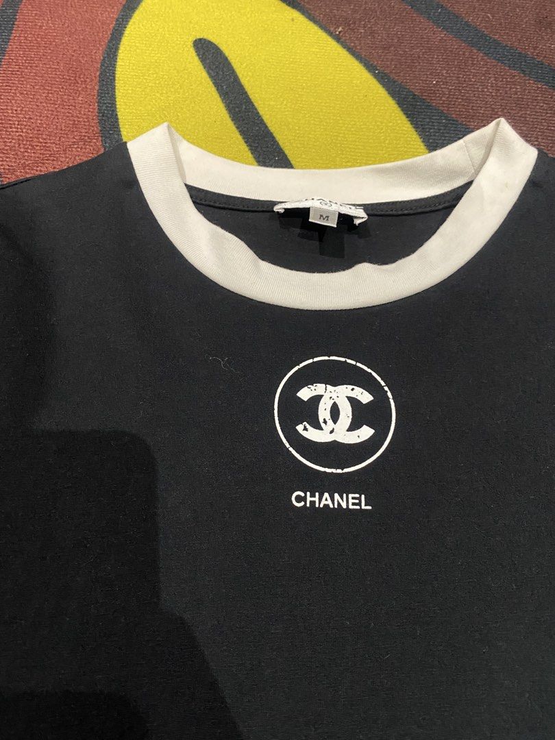 Chanel Black Ringer T-Shirt Size M (Category: Shirts) located in Manila. Submitted by salaspasio80393 (Listing ID 1465284821, Image 2). Description: - Authentic Chanel black cotton t-shirt - Size: Medium (tag attached) - Material: 100% cotton, made in Italy - Design: Contrasting white ringer collar with iconic interlocking CC logo and Chanel lettering on the chest - Fit: Classic casual fit with a clean finish.