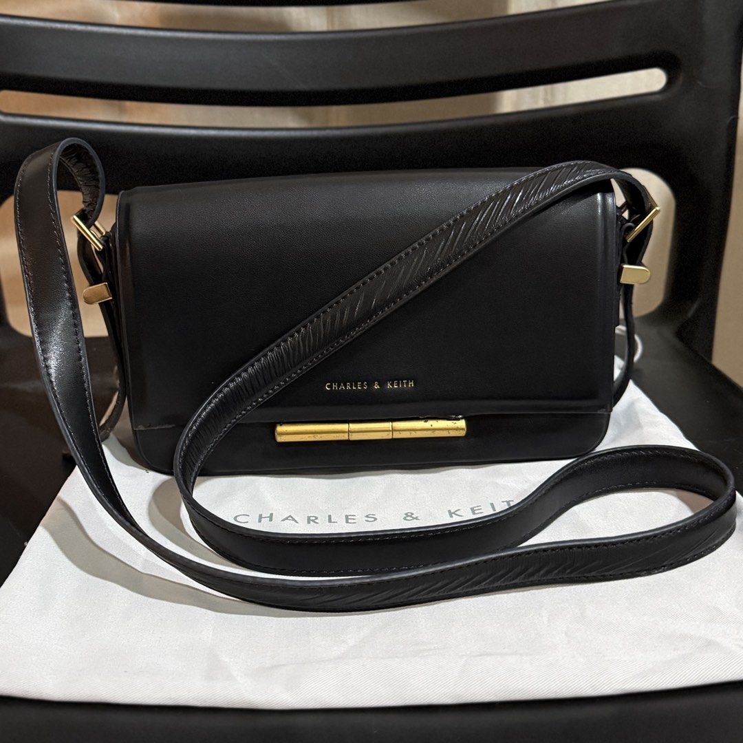 Charles & Keith Black Crossbody Bag (Category: Cross-body Bags) located in Makati City. Submitted by julyco. (Listing ID 1465359195, Image 1). Description: - Brand: Charles & Keith - Color: Classic Black - Style: Structured shoulder bag with elegant gold-tone hardware - Strap: Adjustable with a side buckle for a customizable fit - Interior: Clean black fabric lining with a convenient slip pocket - Inclusion: Comes with the original Charles & Keit