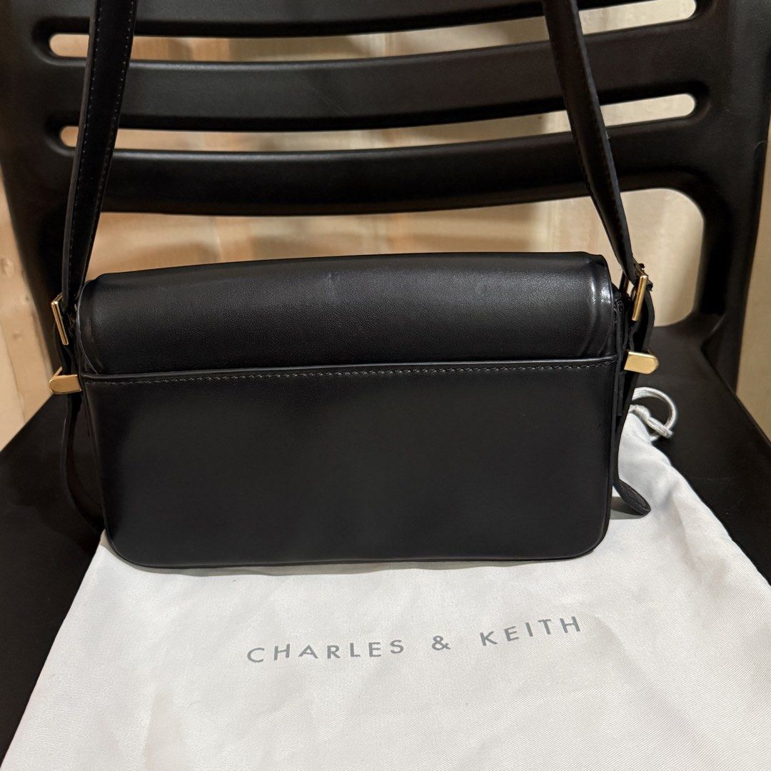 Charles & Keith Black Crossbody Bag (Category: Cross-body Bags) located in Makati City. Submitted by julyco. (Listing ID 1465359195, Image 3). Description: - Brand: Charles & Keith - Color: Classic Black - Style: Structured shoulder bag with elegant gold-tone hardware - Strap: Adjustable with a side buckle for a customizable fit - Interior: Clean black fabric lining with a convenient slip pocket - Inclusion: Comes with the original Charles & Keit