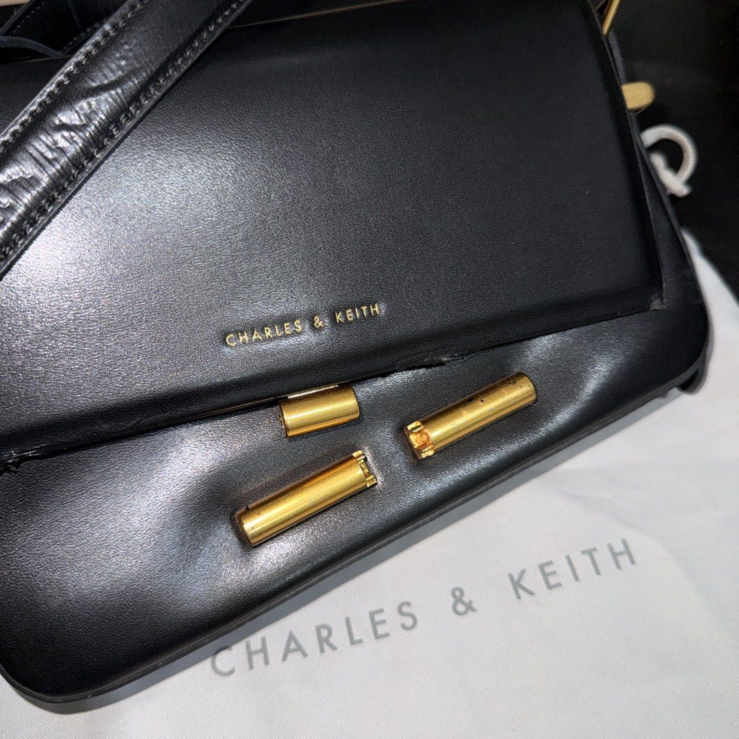 Charles & Keith Black Crossbody Bag (Category: Cross-body Bags) located in Makati City. Submitted by julyco. (Listing ID 1465359195, Image 2). Description: - Brand: Charles & Keith - Color: Classic Black - Style: Structured shoulder bag with elegant gold-tone hardware - Strap: Adjustable with a side buckle for a customizable fit - Interior: Clean black fabric lining with a convenient slip pocket - Inclusion: Comes with the original Charles & Keit