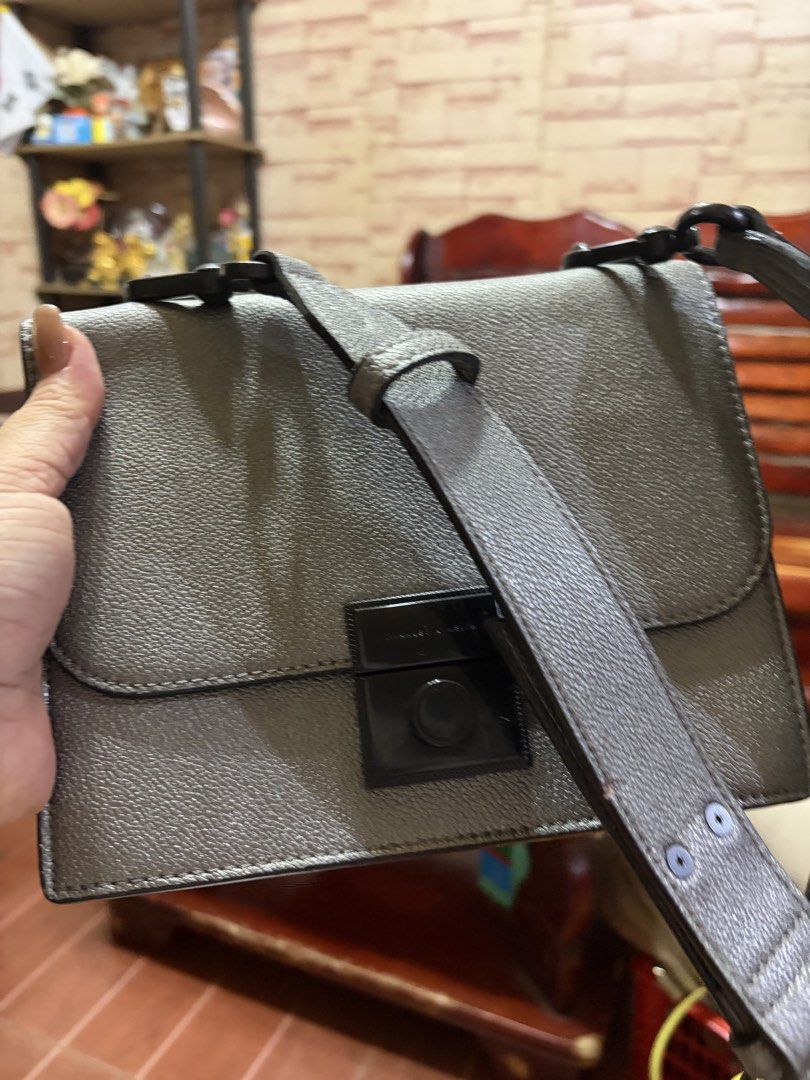 Charles & Keith Gray Crossbody Bag (Category: Cross-body Bags) located in Manila. Submitted by lynnalec25 (Listing ID 1465362927, Image 1). Description: Charles & Keith crossbody bag in textured gray leather. Structured rectangular shape with a flap top closure. Black hardware accent on the front clasp. Thick matching gray strap attached with black swivel hooks. Compact size, great for carrying daily essentials..