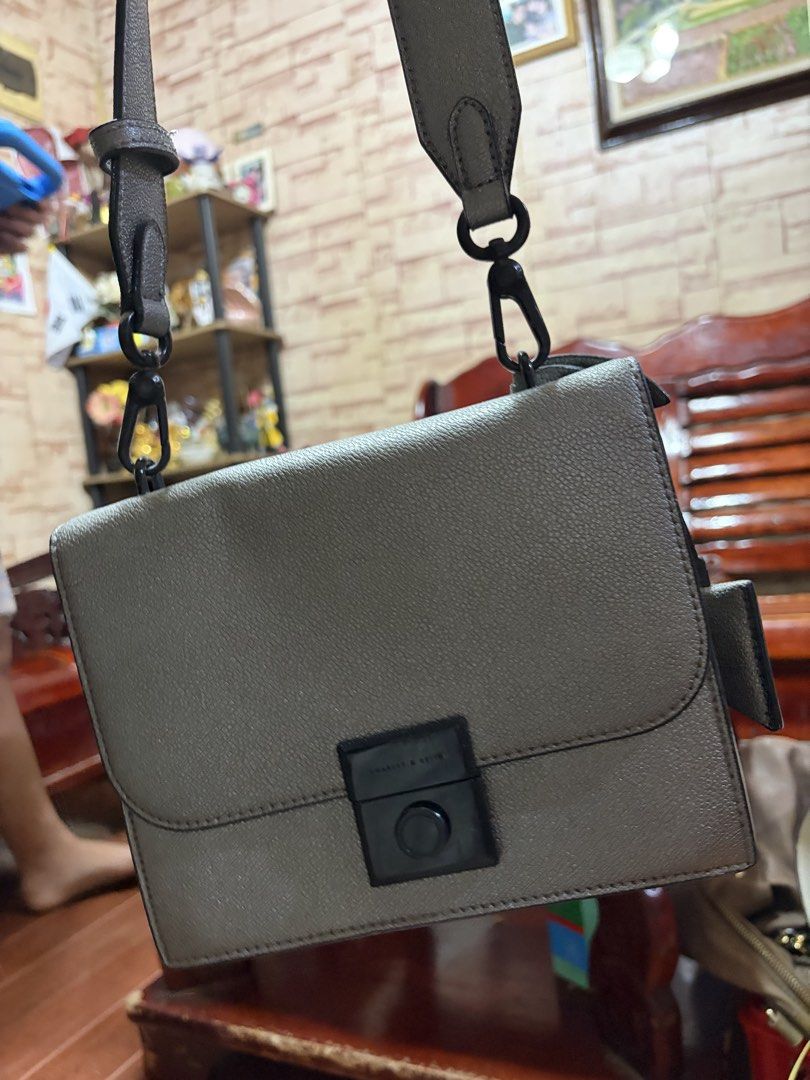 Charles & Keith Gray Crossbody Bag (Category: Cross-body Bags) located in Manila. Submitted by lynnalec25 (Listing ID 1465362927, Image 2). Description: Charles & Keith crossbody bag in textured gray leather. Structured rectangular shape with a flap top closure. Black hardware accent on the front clasp. Thick matching gray strap attached with black swivel hooks. Compact size, great for carrying daily essentials..