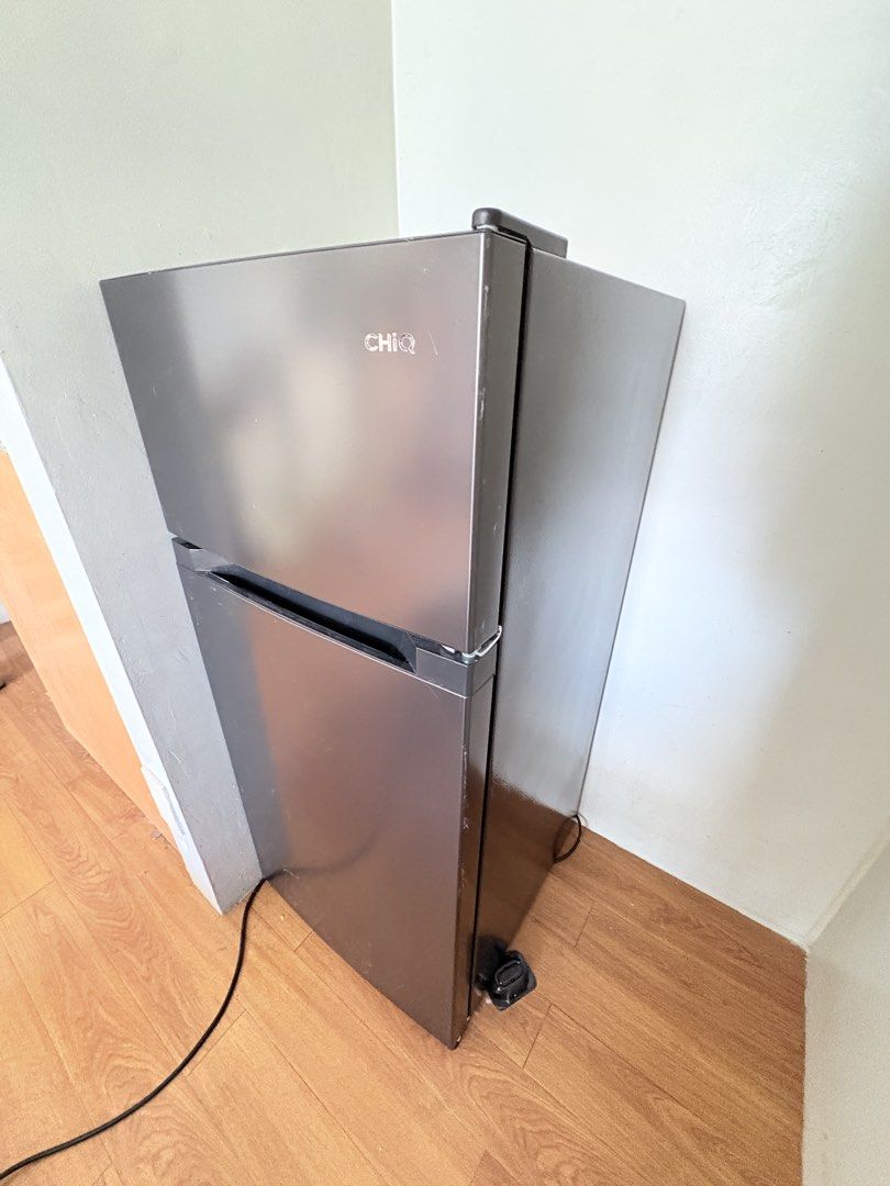 CHiQ Double Door Refrigerator (Category: Refrigerators and Freezers) located in Pasig City. Submitted by petite_declutter (Listing ID 1465377617, Image 2). Description: Dark grey finish, dual door setup. Top freezer, bottom fridge with adjustable wire shelves and clear door bins. Includes crisper drawer at the bottom. Standard two-prong plug. Clean interior, ready for use. Dimensions suit a compact kitchen or dorm room..