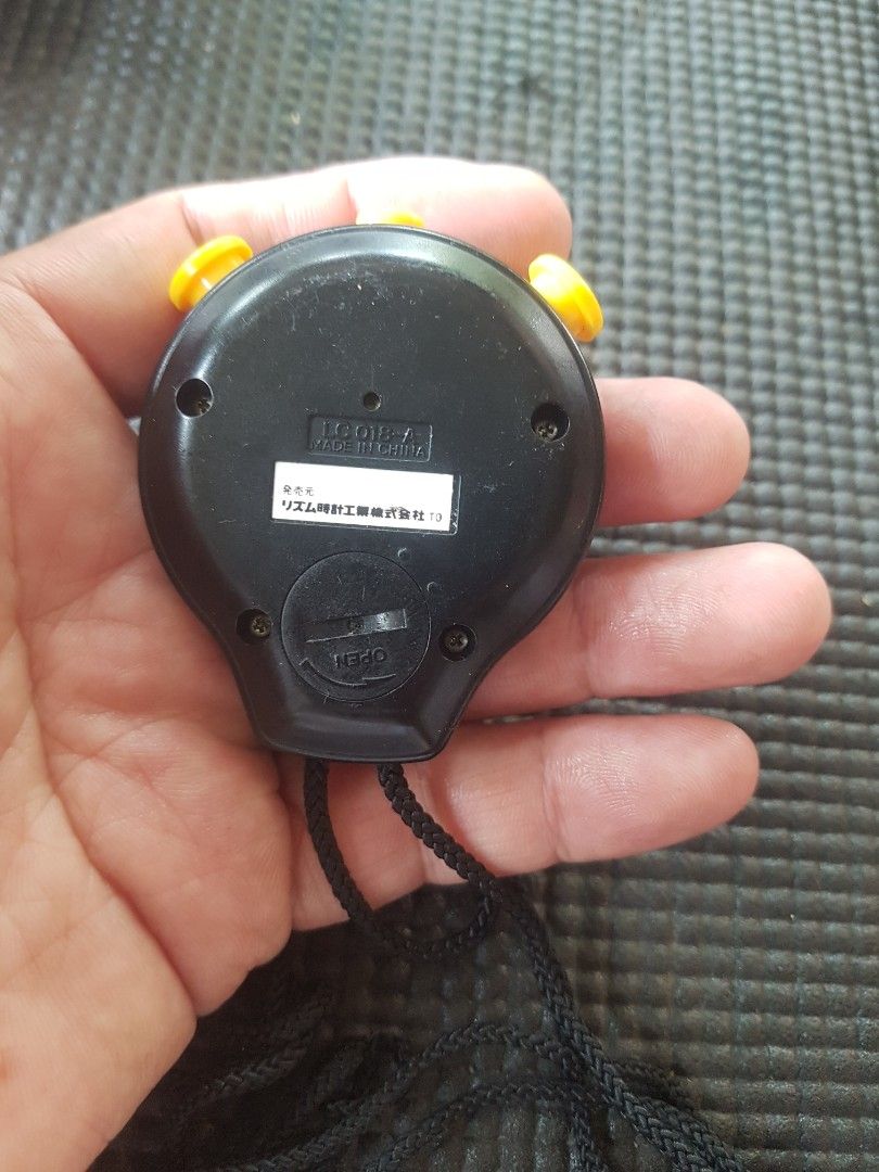 Citizen LC018-A Quartz Stopwatch (Category: Men's Watches) located in Santiago. Submitted by truefire-5f7f (Listing ID 1465178912, Image 3). Description: - Brand/Model: Citizen LC018-A Quartz Sport Chronograph Stopwatch - Design: Black body with bold yellow buttons and accent around the LCD screen - Features: Digital display with time and stopwatch modes - Extras: Includes attached black lanyard strap and rear battery cover - Condition: Working b