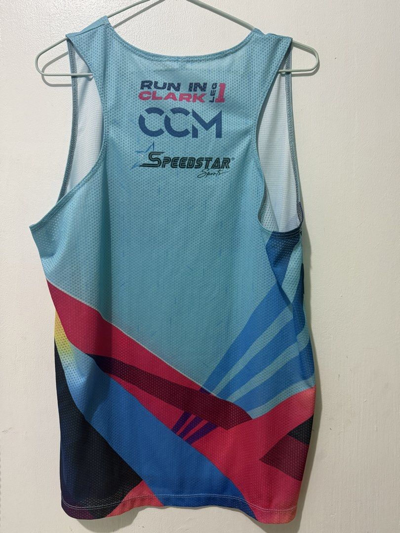 Clark City Night Run 2024 Event Running Singlet (Category: Activewear) located in Manila. Submitted by gjalbaytar05938 (Listing ID 1465380211, Image 2). Description: - Official Clark City Night Run (Leg 1) running singlet - Light blue with vibrant pink, yellow, blue, and black geometric hem graphics - Event branding on the front and sponsor logos (CCM, SpeedStar Sports) on the back - Lightweight, breathable mesh fabric in a sleeveless design.