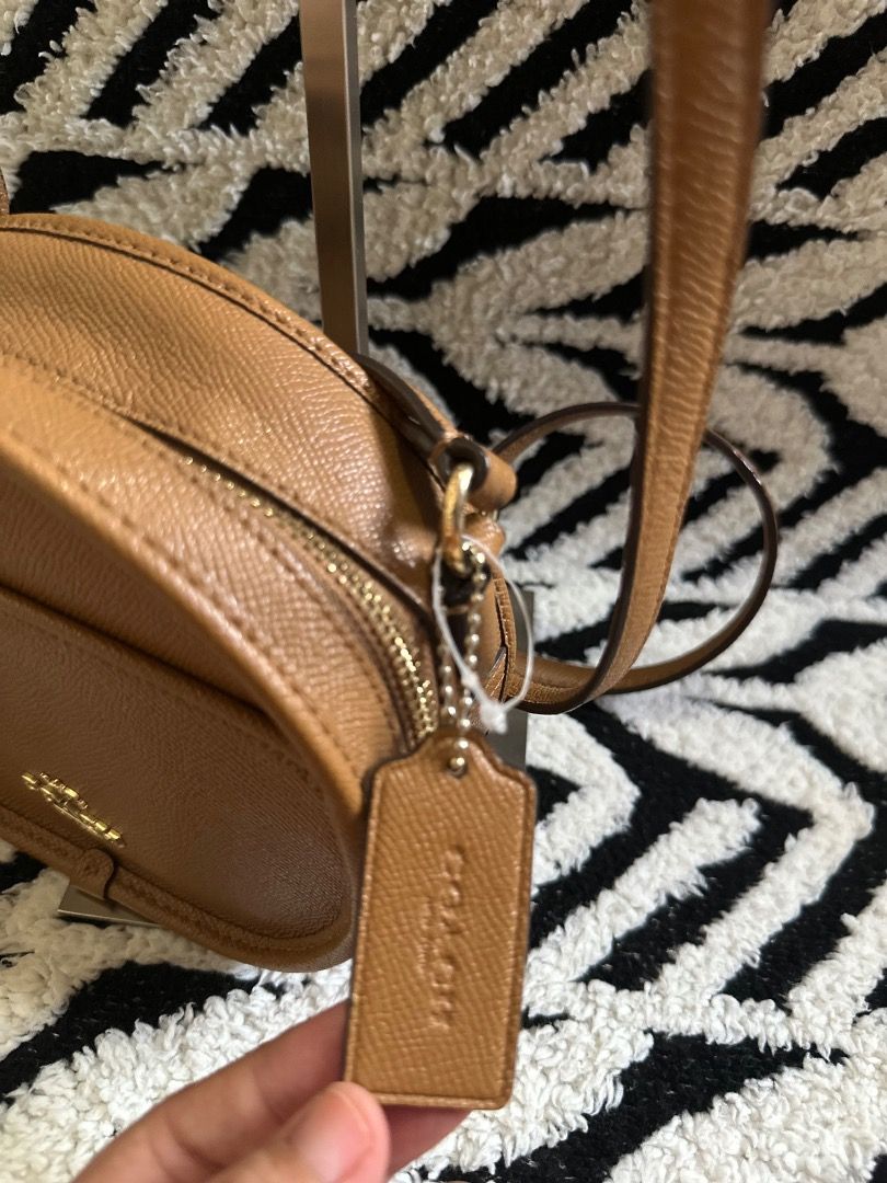 Coach Brown Leather Crossbody Bag (Category: Cross-body Bags) located in Cebu City. Submitted by isellhere123.543 (Listing ID 1465296767, Image 3). Description: Coach round leather crossbody bag in a classic tan brown shade. Structured shape with a front slip pocket and gold-tone hardware. Zip-around closure opens to fabric lining with an inner creed patch. Matching leather hangtag included. Strap is adjustable for comfortable shoulder or crossbo