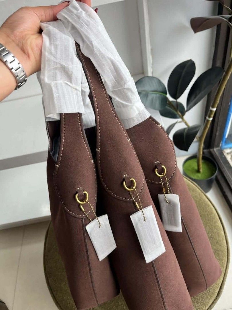Coach Brown Suede Shoulder Bag (Category: Luxury Bags & Wallets) located in Compostela. Submitted by shopbybeverly (Listing ID 1465191758, Image 3). Description: CCH Brooklyn — Made in vietnam 🇻🇳 3 sizes available - Brand new Coach brown suede shoulder bag - Soft suede body with stylish contrast white stitching - Elegant gold-tone hardware details - Handles still wrapped in original protective white paper packaging - Secure magnetic snap top cl