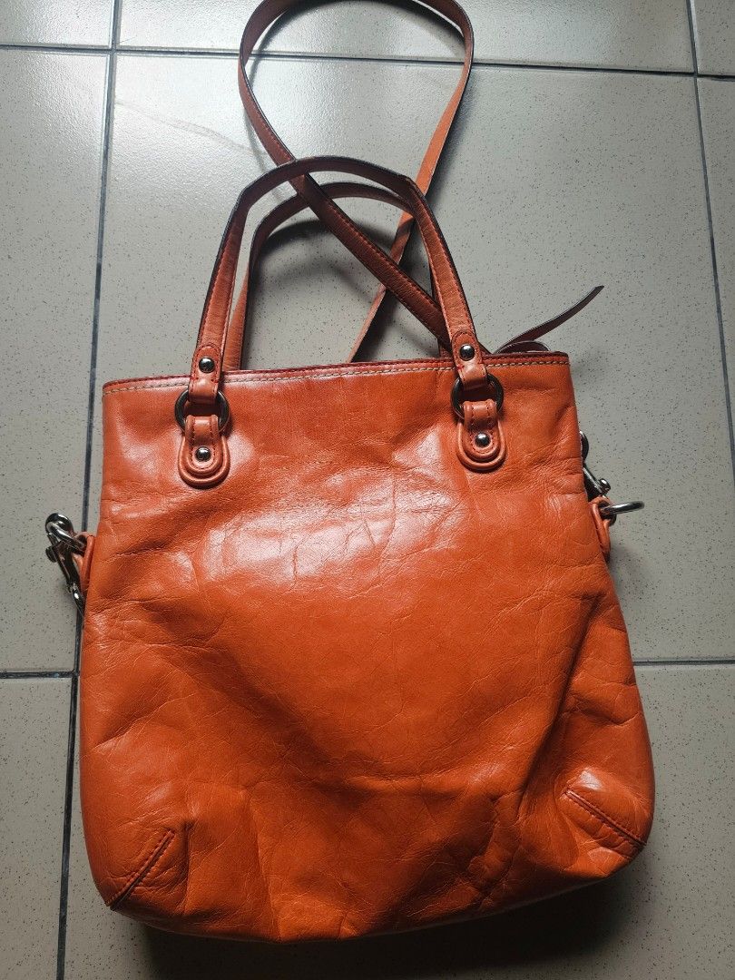 Coach Orange Leather Tote Shoulder Bag (Category: Luxury Bags & Wallets) located in Marikina City. Submitted by charmaine185845 (Listing ID 1465335274, Image 2). Description: - Brand: Coach - Color: Bright orange with contrast white stitching - Material: Soft, slouchy leather - Hardware: Silver-tone with front flap turn-lock closure, rings, and studs - Straps: Dual top carry handles and a detachable long shoulder strap - Interior: Clean setup, id