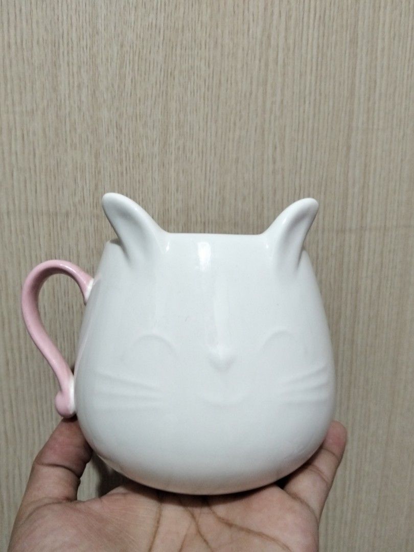 Cute White Ceramic Cat Mug with Pink Handle (Category: Coffee & Tea Tableware) located in Caloocan City. Submitted by agr_shop (Listing ID 1465283464, Image 1). Description: - Adorable white ceramic cat mug featuring raised ears and subtle whisker details - Cute pink handle shaped just like a cat's tail - Round belly design with a generous capacity for your favorite coffee or tea - Clean inside and out, ready for use - Perfect addition to any cat
