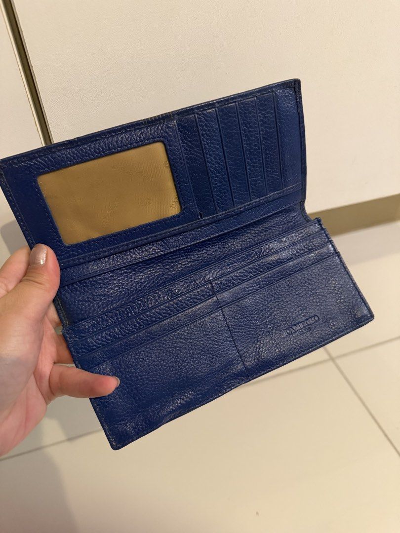 Dambolo Blue Long Leather Wallet (Category: Wallets & Card holders) located in Manila. Submitted by purestar.01 (Listing ID 1465181564, Image 2). Description: - Brand: Dambolo - Color: Blue - Material: Textured leather with front stitched stripe accent and debossed logo - Closure: Secure snap button closure - Interior Features: Plenty of card slots, spacious cash compartments, and a zippered coin pocket - Extra: Convenient clear ID window and cle