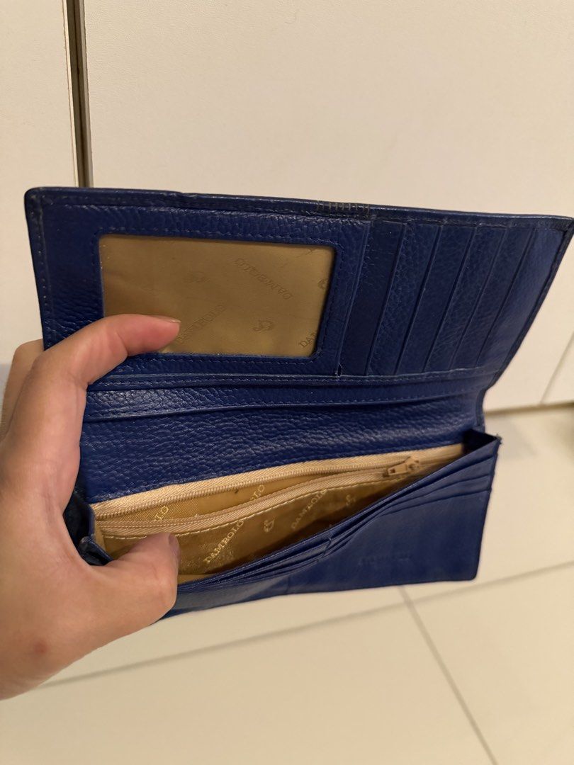 Dambolo Blue Long Leather Wallet (Category: Wallets & Card holders) located in Manila. Submitted by purestar.01 (Listing ID 1465181564, Image 3). Description: - Brand: Dambolo - Color: Blue - Material: Textured leather with front stitched stripe accent and debossed logo - Closure: Secure snap button closure - Interior Features: Plenty of card slots, spacious cash compartments, and a zippered coin pocket - Extra: Convenient clear ID window and cle
