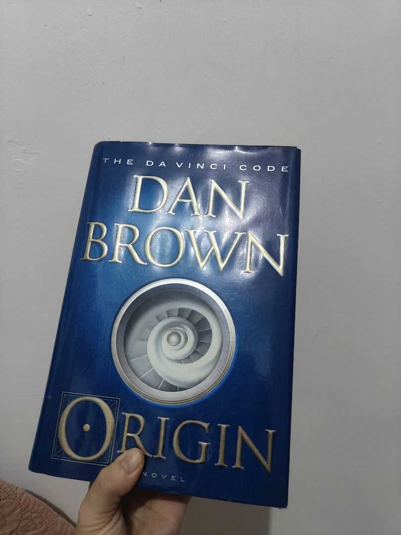 Dan Brown Origin Novel Hardcover Book (Category: Storybooks) located in Lubao. Submitted by fernandezcams (Listing ID 1465266233, Image 1). Description: - Title: Origin by Dan Brown - Format: Hardcover edition with striking blue cover and spiral artwork - Genre: Mystery, thriller, and suspense fiction - Size: Standard hardcover - Condition: Great read, well-kept - Perfect for: Dan Brown fans and thrill-seekers.