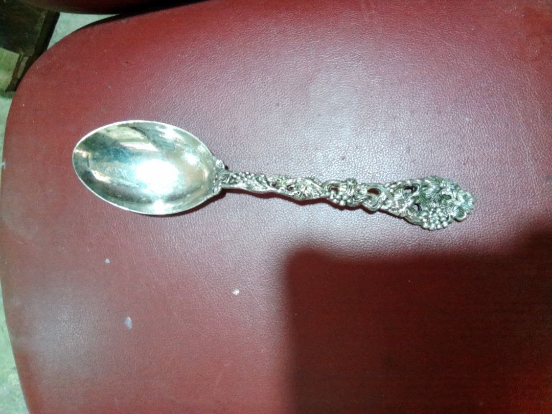 Decorative vintage silver plated spoon with ornate handle (Category: Dinnerware & Cutlery) located in Davao. Submitted by bravemoon_556cd5 (Listing ID 1465241806, Image 3). Description: - Vintage silver spoon with intricate grape and vine handle design - Solid metal construction with natural patina and tarnish from age - Smooth and reflective bowl surface - Palm-sized, approx. standard spoon length - Perfect decorative piece or addition to a vint