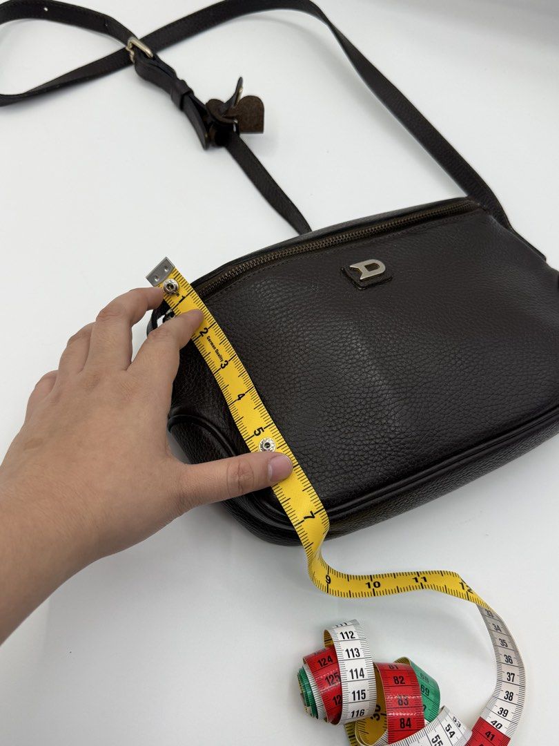 Delvaux (Category: Cross-body Bags) located in Caloocan City. Submitted by rossvault2 (Listing ID 1465237337, Image 3). Description: - Color & Material: Dark brown leather with a stylish pebbled texture - Hardware: Silver-tone D logo on the front and branded zipper pulls - Closure: Secure top zipper closure - Strap: Adjustable shoulder strap with buckle - Size: Compact, roughly 10 inches wide - Interior: Clean lining, perfect for daily essentials