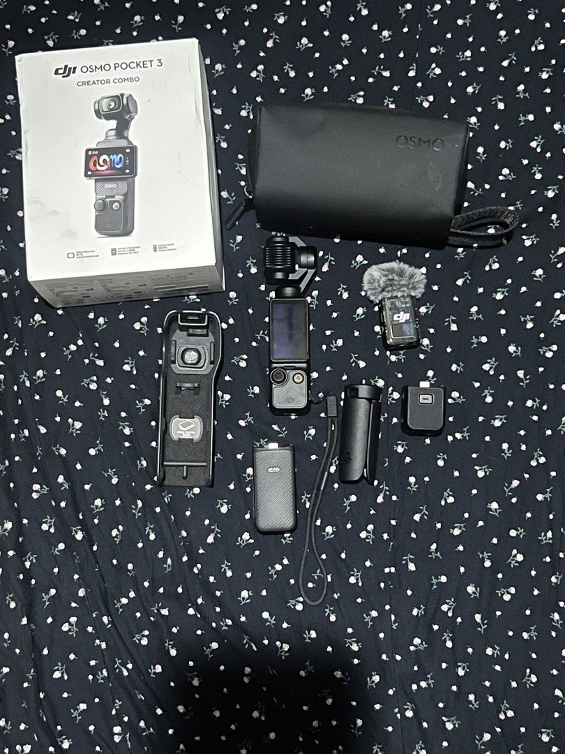 DJI Osmo Pocket 3 Creator Combo (Category: Cameras) located in Manila. Submitted by jacobtesto52166 (Listing ID 1465305714, Image 1). Description: DJI Osmo Pocket 3 Creator Combo package. Includes the camera itself, protective carrying case, mini tripod, DJI Mic 2 transmitter with deadcat wind muff, battery handle, and wide-angle lens attachments in the storage case. Original retail box included. Everything laid out ready for vlogging or video pr
