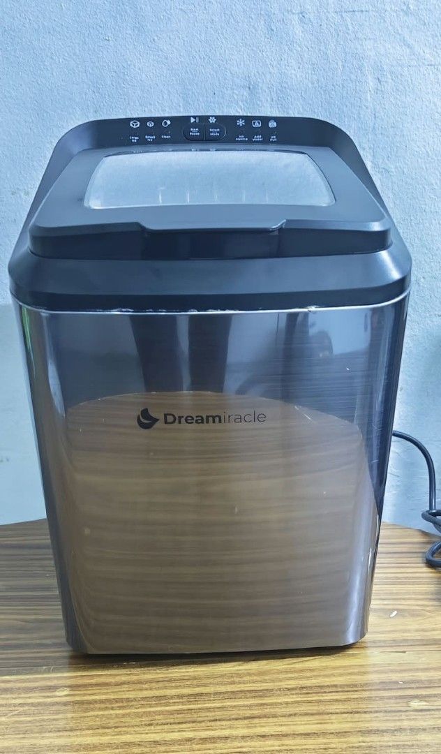 Dreamiracle IM2200-UL Countertop Ice Maker (Category: Refrigerators and Freezers) located in Taguig. Submitted by thrifthub.ph (Listing ID 1465213436, Image 1). Description: Dreamiracle IM2200-UL countertop ice maker. Stainless steel finish with black accents and a clear viewing window on top. Includes removable white plastic ice basket inside. Built-in cooling fan and power cord at the back. Manufactured May 2021. Operates on 120V AC. Powers on 