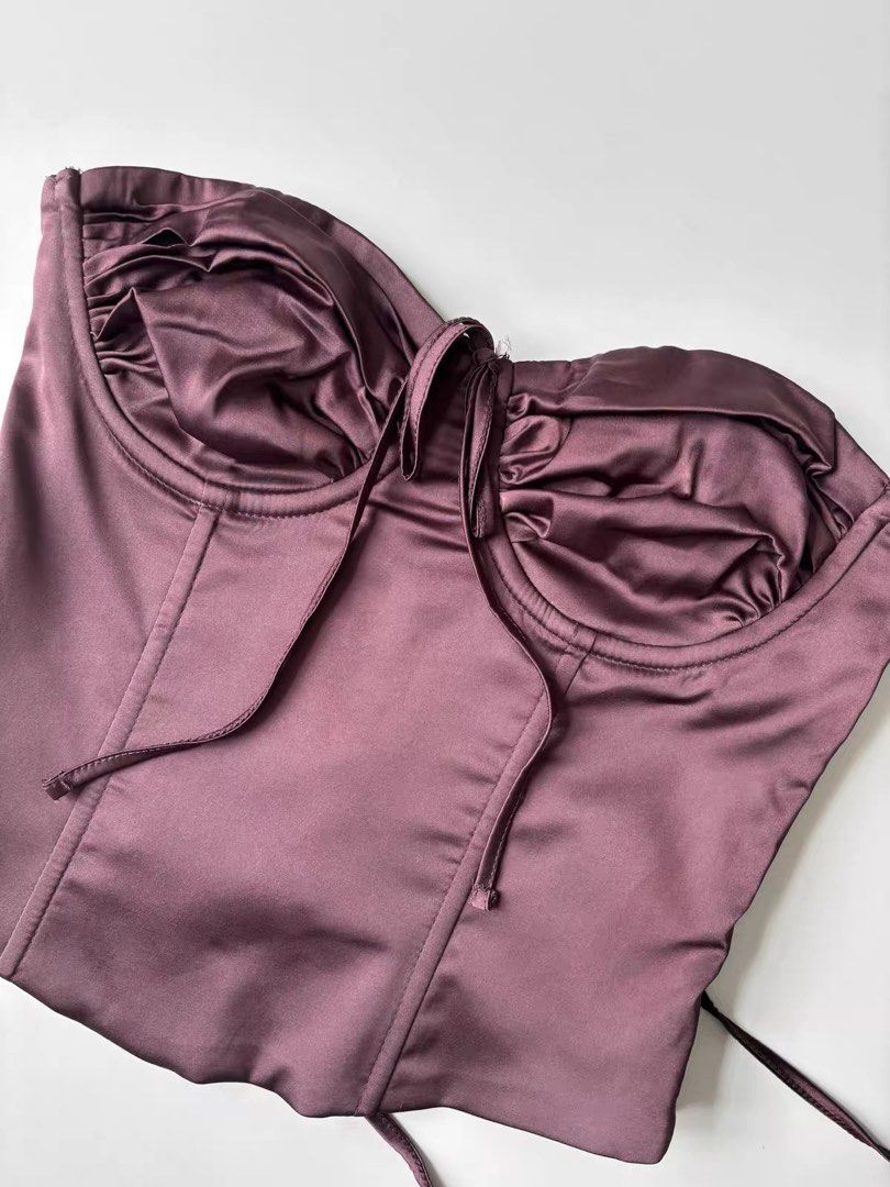 Edikted Satin Corset Top in Plum (Category: Sleeveless) located in Quezon City. Submitted by shoppingspreewithme (Listing ID 1465222806, Image 1). Description: - Color: Plum - Material: Smooth satin with a slight sheen and inner lining - Support: Structured underwire cups with gathered fabric - Closure: Side zipper and adjustable lace-up back with silver-tone metal eyelets - Fit: Cropped length with a flattering dipped hem.