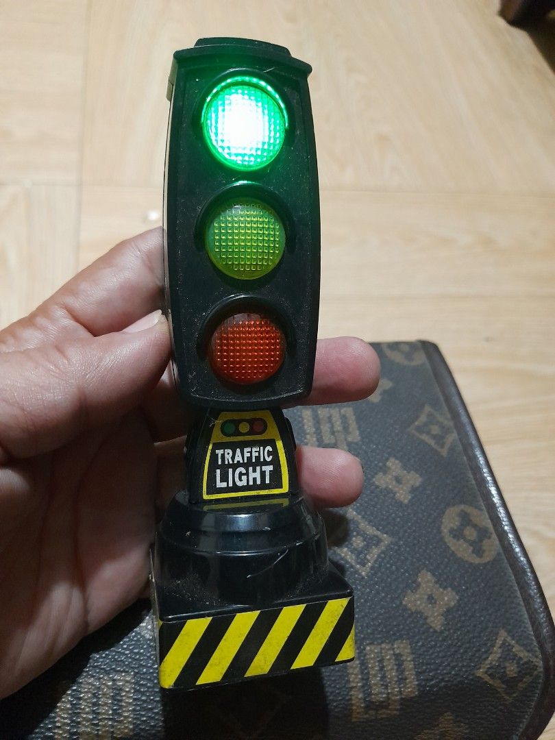 Electronic Traffic Light Toy with Working Lights (Category: Kids Toys) located in Bocaue. Submitted by marajapansurplus (Listing ID 1465287727, Image 2). Description: - Plastic traffic light toy with working red, yellow, and green lights - Button-activated light cycling feature - Battery-operated with battery cover intact on the back - Detailed with yellow warning stripes on the side handle - Perfect fun prop for kids' toy cars or as a unique des