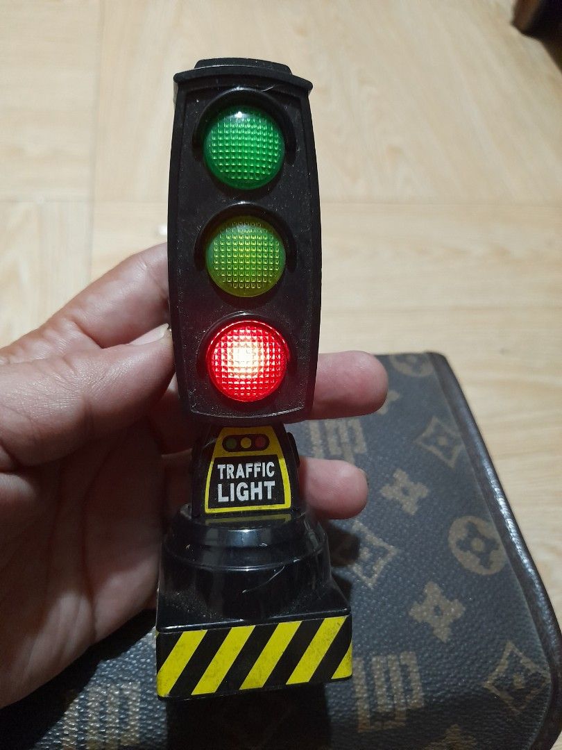 Electronic Traffic Light Toy with Working Lights (Category: Kids Toys) located in Bocaue. Submitted by marajapansurplus (Listing ID 1465287727, Image 3). Description: - Plastic traffic light toy with working red, yellow, and green lights - Button-activated light cycling feature - Battery-operated with battery cover intact on the back - Detailed with yellow warning stripes on the side handle - Perfect fun prop for kids' toy cars or as a unique des