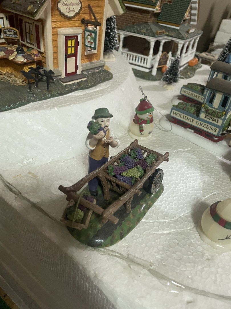 Department 56 Fall Figurines (Category: Figurines & Statues) located in Quezon City. Submitted by inamocha (Listing ID 1465373476, Image 3). Description: - Piece 1: Man holding grapes next to a wooden wheelbarrow filled with grapes (1500) - Piece 2: Children building a scarecrow with a carved pumpkin head on a hay bale (1500) - Hand-painted details with autumn leaves on the base - Ideal for holiday setups, miniature villages, and seasonal home de
