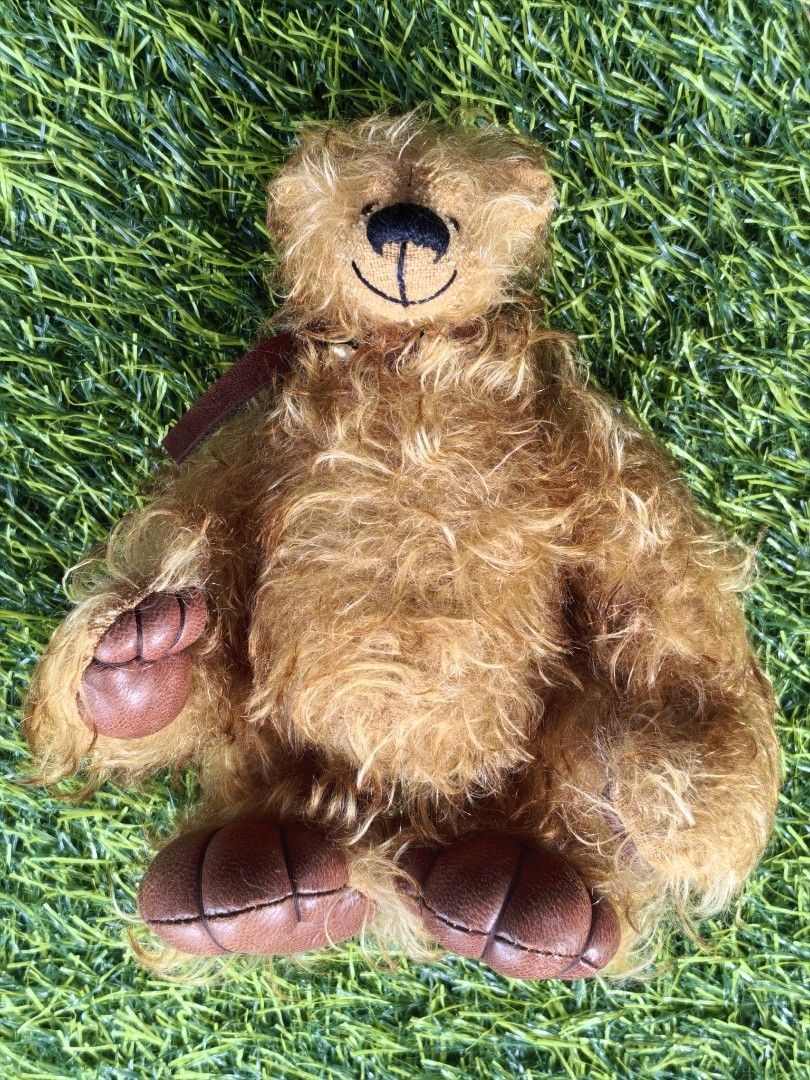 Fluffy Brown Teddy Bear with Leather-like Paws (Category: Plushies & Soft Toys) located in Paranaque City. Submitted by furugiyafinds (Listing ID 1465225817, Image 1). Description: Fuzzy golden brown teddy bear with shaggy fur. Dark brown faux leather paw pads with stitched details. Embroidered black nose and smiling mouth. Small brown ribbon around the neck. Soft stuffed body, fully jointed limbs. Clean fur, well-kept toy from a smoke-free home.