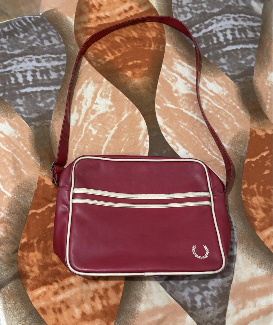 Fred Perry Red White Stripe Shoulder Bag (Category: Luxury Bags & Wallets) located in Manila. Submitted by calvinomateo14 (Listing ID 1465179424, Image 1). Description: - Brand: Fred Perry - Material: Red faux leather with white piping details - Design: Double stripe front pocket and embroidered laurel wreath logo - Storage: Main zip compartment and front slip pocket - Strap: Adjustable shoulder strap attached - Condition: Some wear marks and min