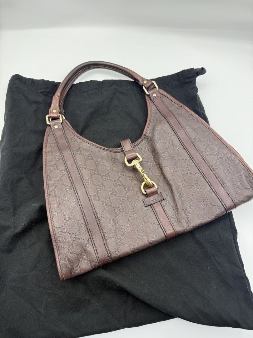 Gucci Jackie (Category: Luxury Bags & Wallets) located in Caloocan City. Submitted by rossvault2 (Listing ID 1465240449, Image 3). Description: - Brand: authentic Gucci - Style: Hobo bag with piston closure - Material: Dark brown leather with embossed GG monogram - Details: Vertical leather strips and gold-tone hardware - Interior: Horsebit patterned fabric lining with a zipped pocket - Inclusions: Original black Gucci dust bag - Condition: Excel