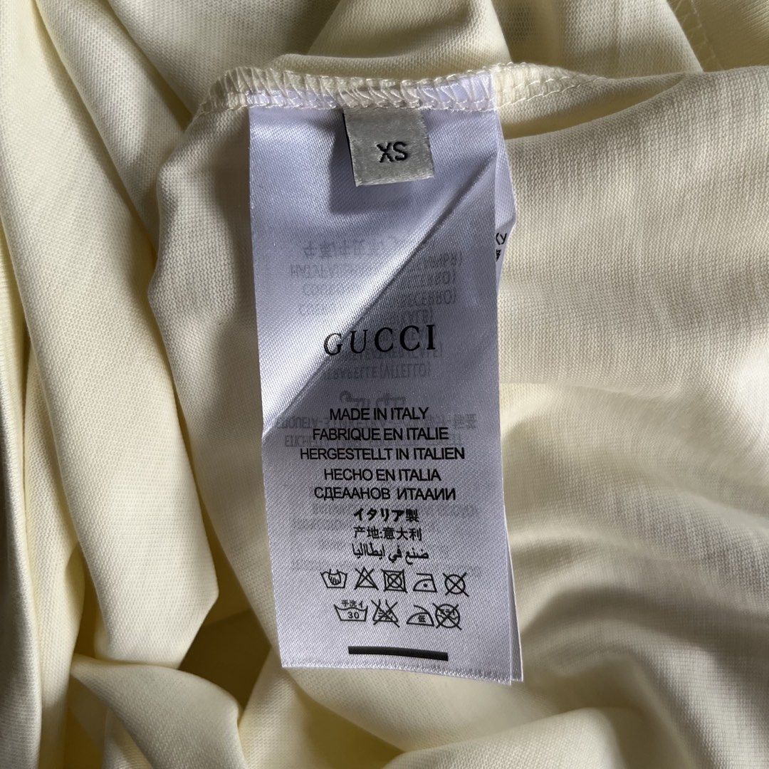 Gucci T-Shirt (Category: Activewear) located in Davao. Submitted by gotchastuff (Listing ID 1465268073, Image 3). Description: - Brand: Gucci - Color: Cream - Size: XS - Dimes 21x28.5 - Condition: Brand new with original tags attached - Details: Graphic print with dripping trefoil logo and Gucci lettering, classic crew neck, short sleeves - Origin: Made in Italy.