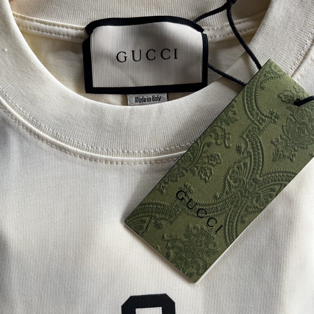 Gucci T-Shirt (Category: Activewear) located in Davao. Submitted by gotchastuff (Listing ID 1465268073, Image 2). Description: - Brand: Gucci - Color: Cream - Size: XS - Dimes 21x28.5 - Condition: Brand new with original tags attached - Details: Graphic print with dripping trefoil logo and Gucci lettering, classic crew neck, short sleeves - Origin: Made in Italy.