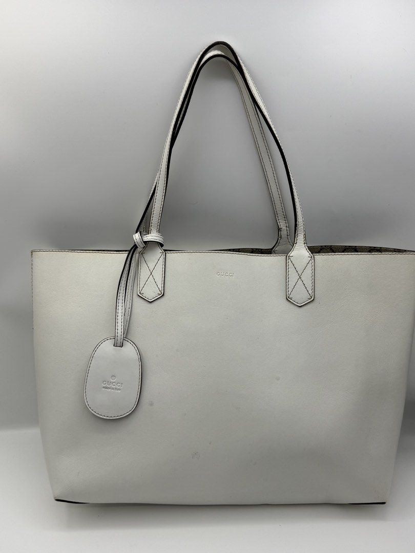 Gucci White Reversible Leather Tote Bag (Category: Tote Bags) located in Caloocan City. Submitted by rossvault2 (Listing ID 1465232736, Image 1). Description: - Gucci white leather tote bag - Reversible design with classic GG monogram fabric interior - Features comfortable dual shoulder straps and matching embossed logo hanging tag - Spacious interior, perfect as an everyday carryall - Condition: Shows visible marks and smudges on the exterior wh