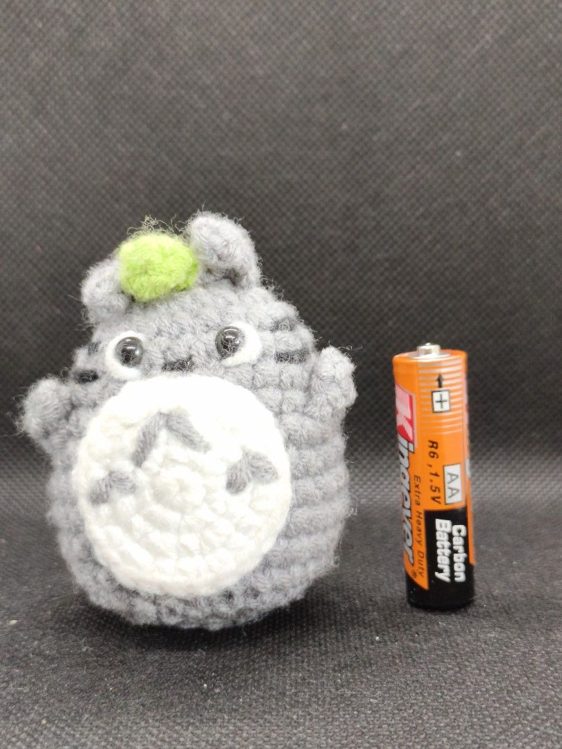 Handmade Crochet Totoro Plush Toy (Category: Plushies & Soft Toys) located in Rizal. Submitted by kencamara (Listing ID 1465251742, Image 1). Description: - Handmade grey and white crochet Totoro plush toy - Features a small green detail on top of the head - Compact size (roughly the height of an AA battery) - Neat stitching all around - Perfect desk companion or room decor for Studio Ghibli fans.