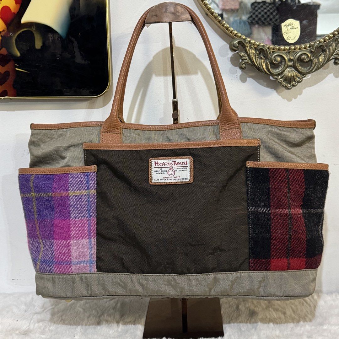 Harris Tweed Patchwork Tote Bag Brown Purple Plaid (Category: Tote Bags) located in Rizal. Submitted by houseofbell (Listing ID 1465374504, Image 1). Description: - Authentic Harris Tweed tote bag with official orb label - Brown main body with stylish green-tinted canvas panels - Unique side slip pockets in purple-pink and red-black wool plaid - Premium leather handles, trim, and large front pocket - Protective metal feet on the bottom base Dimen