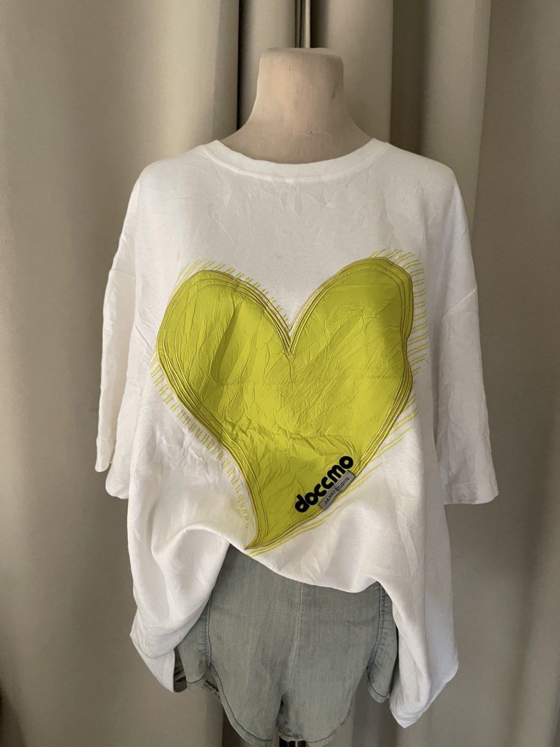 HEAVY COTTON Doccmo White TEE (Category: Shirts) located in Cainta. Submitted by zlove111 (Listing ID 1465172256, Image 2). Description: - Brand: Doccmo Jia Hao Studios - Style: White oversized streetwear tee with crew neck and short sleeves - Design: Large lime yellow heart graphic with embroidered outlines and branded tag detail - Fit: Loose and comfortable - Condition: Good overall, but has a couple of small faint yellowish spots near the top 