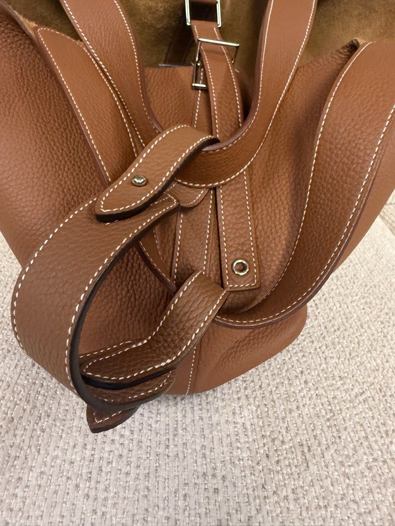 Hermes Picotin Lock 26 Taurillon Clemence Gold (Category: Luxury Bags & Wallets) located in Makati City. Submitted by dgcurated09 (Listing ID 1465366389, Image 2). Description: - Color: Tan - Material: Textured grained leather with natural suede interior - Hardware: Silver-toned metal with protective feet on a structured flat base - Handles: Two top handles featuring stylish white contrast stitching - Closure: Center strap with a secure silver bu