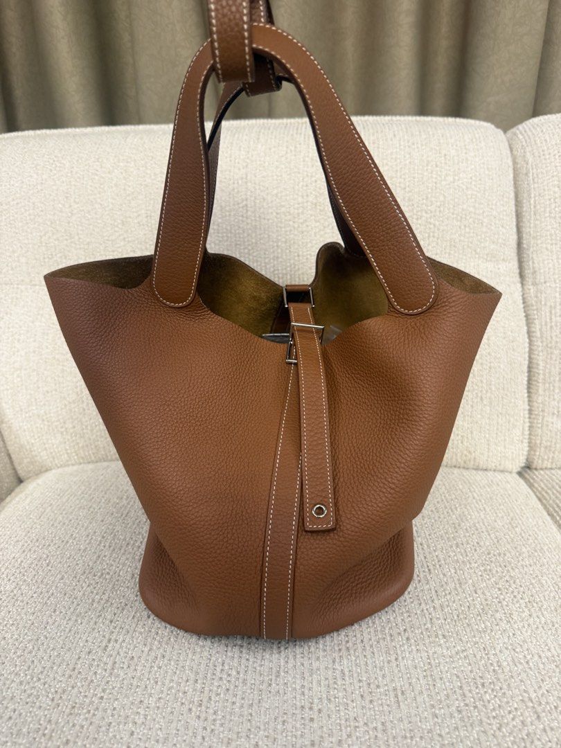 Hermes Picotin Lock 26 Taurillon Clemence Gold (Category: Luxury Bags & Wallets) located in Makati City. Submitted by dgcurated09 (Listing ID 1465366389, Image 1). Description: - Color: Tan - Material: Textured grained leather with natural suede interior - Hardware: Silver-toned metal with protective feet on a structured flat base - Handles: Two top handles featuring stylish white contrast stitching - Closure: Center strap with a secure silver bu