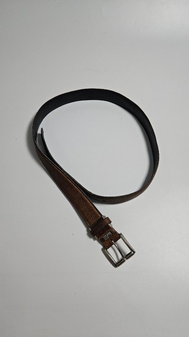 Issey miyake Design Studio Brown Leather Belt (Category: Belts) located in Alfonso. Submitted by jbcamet (Listing ID 1465241943, Image 2). Description: - Brand: Mistake Design Studio - Material: Brown leather with textured grain finish and solid black reverse backing - Hardware: Silver metal buckle with engraved brand plate near the closure - Fit: Multiple adjustment holes for a customizable fit - Condition: Shows natural wear creases from regula