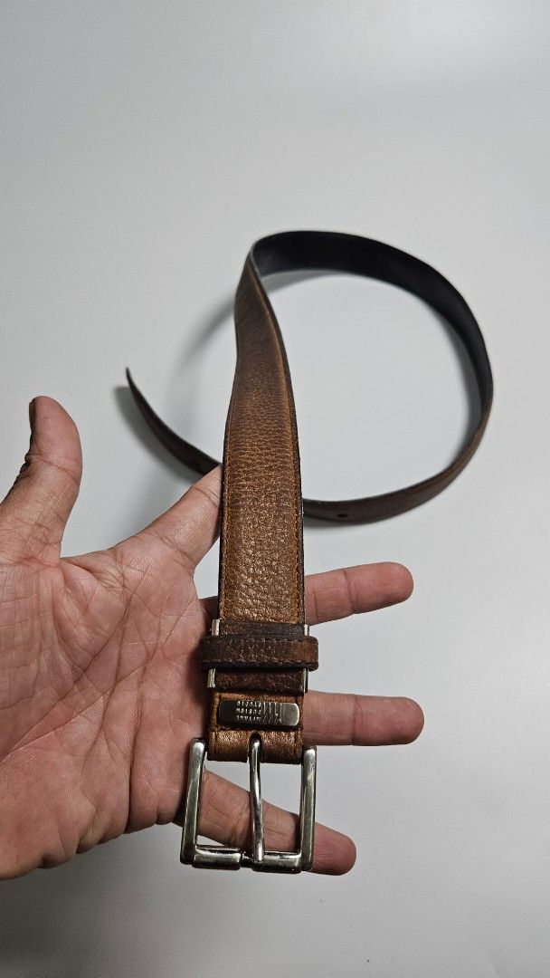 Issey miyake Design Studio Brown Leather Belt (Category: Belts) located in Alfonso. Submitted by jbcamet (Listing ID 1465241943, Image 3). Description: - Brand: Mistake Design Studio - Material: Brown leather with textured grain finish and solid black reverse backing - Hardware: Silver metal buckle with engraved brand plate near the closure - Fit: Multiple adjustment holes for a customizable fit - Condition: Shows natural wear creases from regula