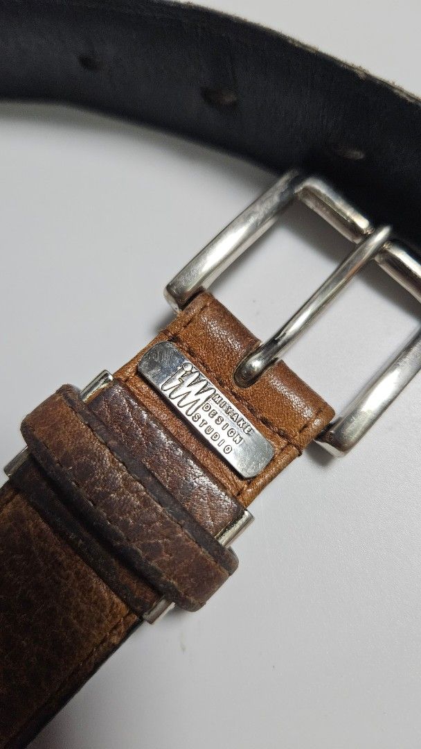 Issey miyake Design Studio Brown Leather Belt (Category: Belts) located in Alfonso. Submitted by jbcamet (Listing ID 1465241943, Image 1). Description: - Brand: Mistake Design Studio - Material: Brown leather with textured grain finish and solid black reverse backing - Hardware: Silver metal buckle with engraved brand plate near the closure - Fit: Multiple adjustment holes for a customizable fit - Condition: Shows natural wear creases from regula