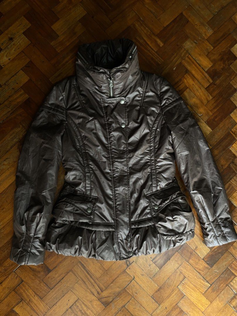 KAKO Brown Puffer Winter Jacket Size 38 (Category: Coats, Jackets and Outerwear) located in Taguig. Submitted by cherylmnl.vintage (Listing ID 1465220079, Image 1). Description: - Brand: KAKO - Size: 38 (tag on collar) - Color: Brown with a smooth, shiny fabric finish - Design: High neck funnel collar and front zip closure with snap buttons - Pockets: Convenient flap pockets on both sides - Fit: Fitted waist with a flattering, slightly flared ruf