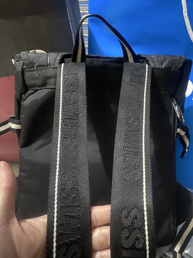 K-Swiss Black Backpack with Striped Details (Category: Backpacks) located in San Narciso. Submitted by boypablo1998 (Listing ID 1465294432, Image 2). Description: - Brand: K-Swiss - Color: Classic Black - Design: Vertical stripes on the front flap and straps with a metal logo badge - Storage: Zippered front pocket and secure main compartment with dual buckle straps - Details: Back straps feature woven K-Swiss text branding with white piping - Fea