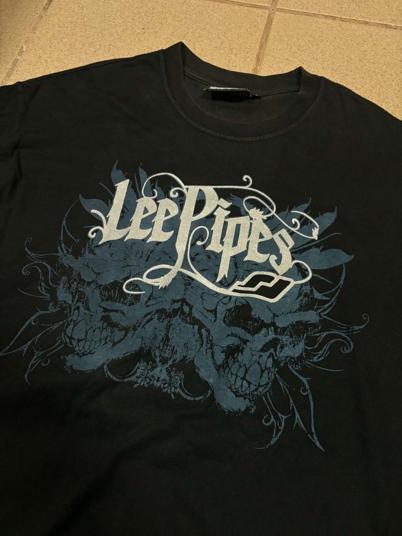 Lee Pipes Black Graphic Tee Skull Y2K (Category: Tshirts & Polo Shirts ) located in Caloocan City. Submitted by joshuadyogi0122 (Listing ID 1465181887, Image 2). Description: - Brand: Lee Pipes - Color: Black - Size: Large - Design: Large skull and scroll front graphic with small back collar logo - Fit: Standard fit with classic crew neck - Details: Interior tag with care instructions included.