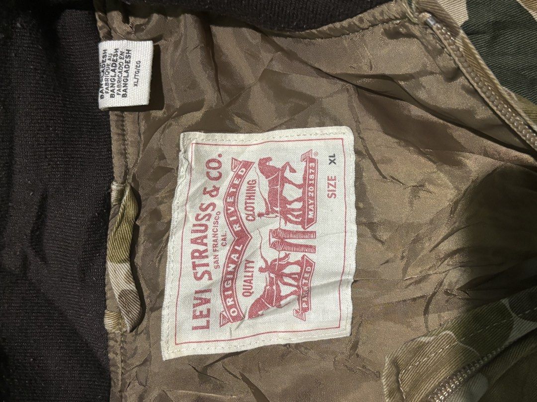Levi's Camouflage Bomber Jacket Size XL (Category: Coats, Jackets and Outerwear) located in Manila. Submitted by kyosei00 (Listing ID 1465314131, Image 2). Description: - Brand: Levi's - Item: Camouflage Bomber Jacket - Size: XL - Origin: Made in Bangladesh - Closure: Full front zip - Details: Brown ribbed collar, cuffs, and hem, fully lined interior - Style: Utility aesthetic, perfect for everyday wear.