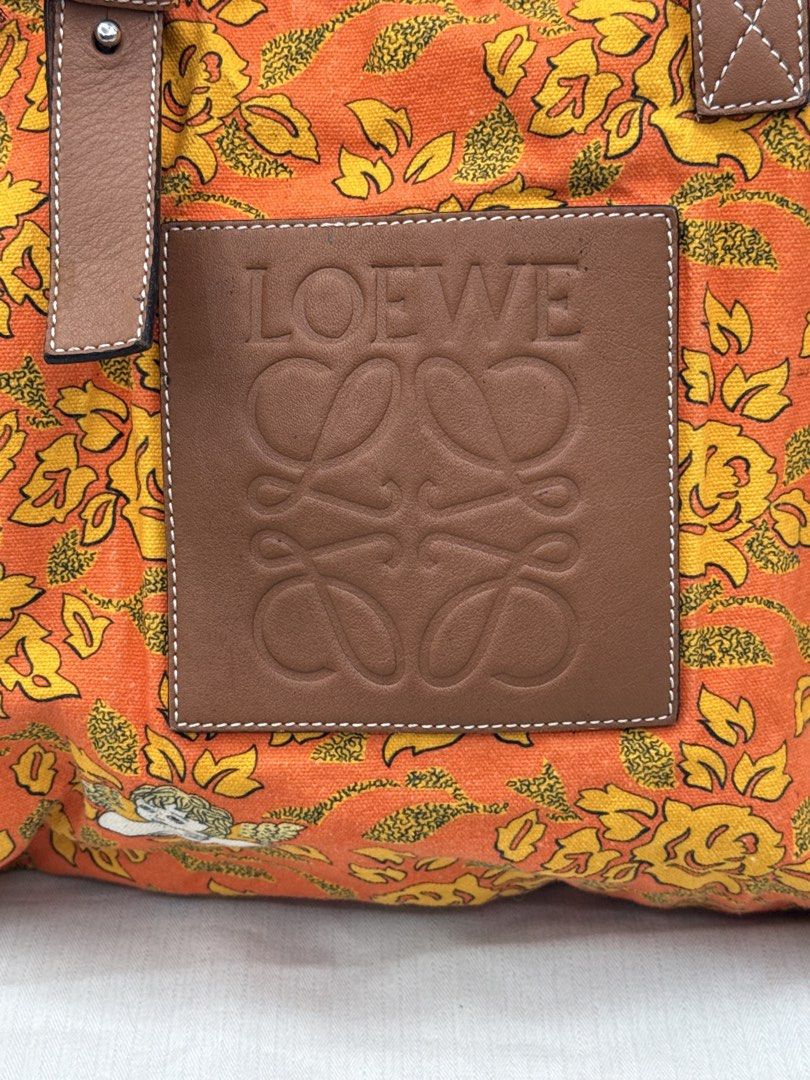 Loewe (Category: Tote Bags) located in Caloocan City. Submitted by rossvault2 (Listing ID 1465231073, Image 3). Description: - Brand: authentic Loewe designer canvas tote bag - Design: Vibrant orange canvas with yellow floral pattern and cherub graphics - Details: Large embossed Loewe leather patch on the front - Straps: Brown leather shoulder straps with adjustable buckles - Interior: Spacious enough for all your daily essentials - Condition/Inc