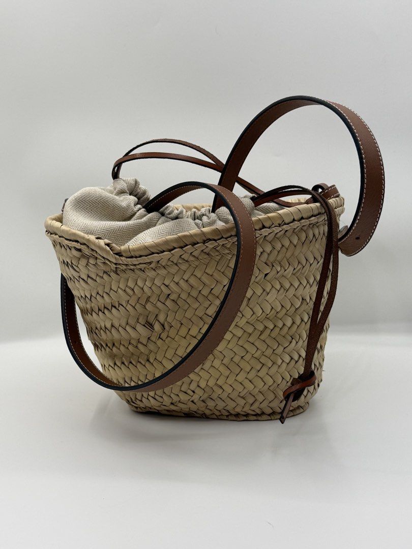 Loewe (Category: Shoulder Bags) located in Caloocan City. Submitted by rossvault2 (Listing ID 1465237591, Image 3). Description: Loewe bucket basket bag, woven straw body with tan leather square patch embossed with anagram logo. Brown leather adjustable shoulder straps. Interior has a herringbone patterned drawstring canvas pouch. Natural straw construction with classic craftsmanship. Great daily carryall for summer days. -signs of used inside/ d