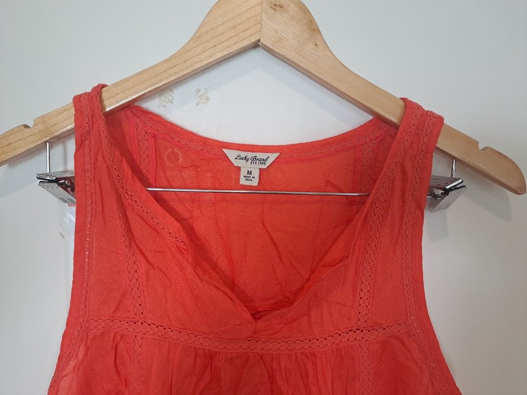 Lucky brand sleeveless (Category: Sleeveless) located in Manila. Submitted by joanbalde39643 (Listing ID 1465246593, Image 2). Description: This is a vibrant coral-orange sleeveless tank blouse from the brand Lucky Brand. It features a bohemian-inspired split V-neckline with delicate crochet lace trimming around the collar and a lightly pleated, flowing silhouette..