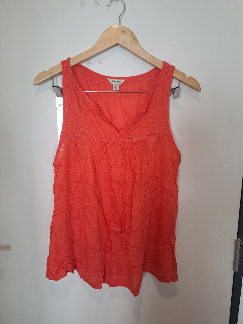 Lucky brand sleeveless (Category: Sleeveless) located in Manila. Submitted by joanbalde39643 (Listing ID 1465246593, Image 1). Description: This is a vibrant coral-orange sleeveless tank blouse from the brand Lucky Brand. It features a bohemian-inspired split V-neckline with delicate crochet lace trimming around the collar and a lightly pleated, flowing silhouette..